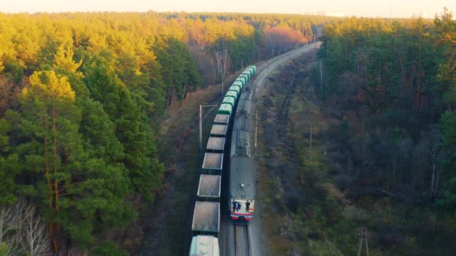 Aerial view of two trains - freight and commuter - traveling towards each other in autumn forest at sunset