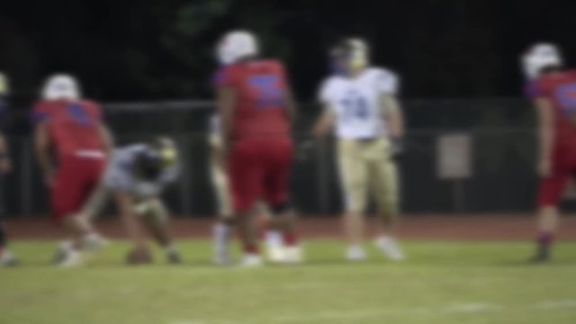 Defocused football players lining up on line of scrimmage ball snap and play