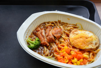 noodle with spicy sauce, sliced chicken, fried egg, broccoli, corn and carrot, instant food, delicatessen, frozen food in mini mart or supermarket ready to eat (selective focus)