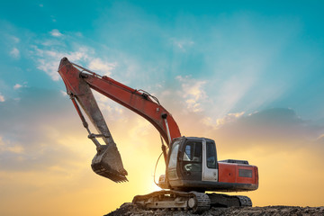 Excavator in construction site on sunset sky background