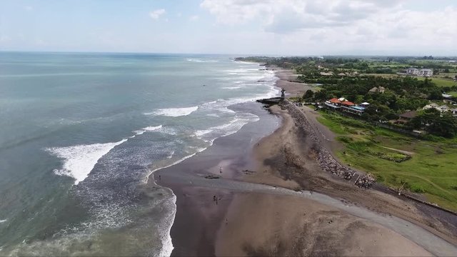 Amazing scenery of island having plenty of palm trees and bushes, some small houses, shore coast line, boats and beautiful sea with bluel water surface reflecting clear sky in summer time.