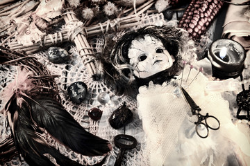 Vintage still life with scary voodoo doll in bride dress, black candle, cross and feathers. Magic...
