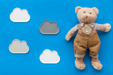 Toys for newborn baby set with teddy bear and clouds on blue background flat lay