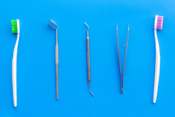 Tooth care with toothbrush and dentist instruments. Set of cleaning products for teeth on blue background top view