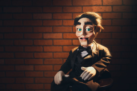 scary ventriloquist doll sitting on a stool.
