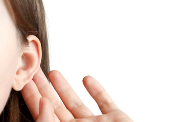 The girl listens attentively with her palm to her ear, close-up isolated on white background,...