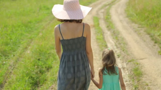 Mother and her daughter walking along a rural road