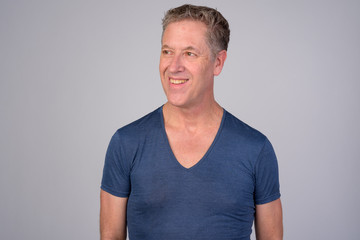 Fototapeta premium Happy mature man smiling while thinking against white background