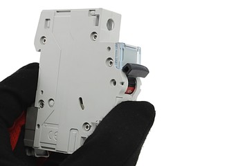 Circuit breaker module for domestic fuse box with robust plastic lever, held in left hand in latex glove, white background. 