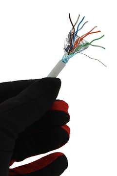 Ending of shielded lan network cable STP cat 5E held in left hand in black glove, white background. 
