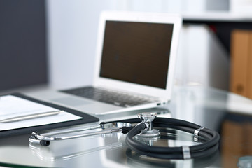 Stethoscope, prescription medical form lying on glass table with laptop computer. Medicine or pharmacy concept. Medical tools at doctor working table