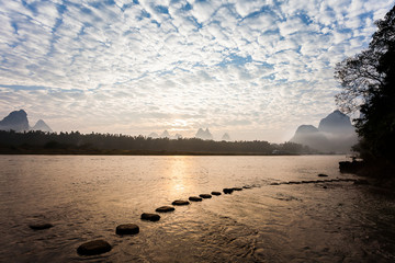 Early morning altocumulus clouds ,river  and stepping stone  - obrazy, fototapety, plakaty