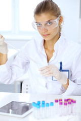 Fototapeta premium Female scientific researcher or blood test assistant at work in laboratory. Science, medicine and pharmacy concept