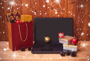 Laptop, gifs and shopping bag full of christmas gifts