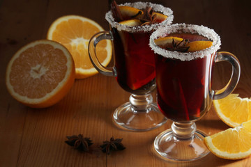 Two cups with ready mulled wine with anise, cinnamon and nuts around	