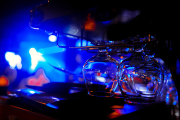 Glasses of wine. Glasses hanging above the bar in the restaurant. Empty glasses for wine. Wine and martini glasses in shelf above a bar rack in restaurant. blue lights, blue background, night life