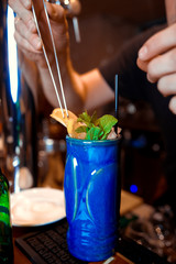 Obraz na płótnie Canvas closeup of a barman using pliers to decorate his cocktail