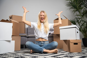 Image of displeased woman sitting on floor among cardboard boxes