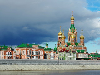 Fototapeta na wymiar Orthodox Church on the coast of beautiful river. Colorful background with golden domes.