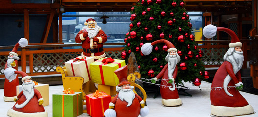 Christmas and new year street decorations with xmas tree santa claus and elf figurines delivering gifts outdoors in winter holidays day.