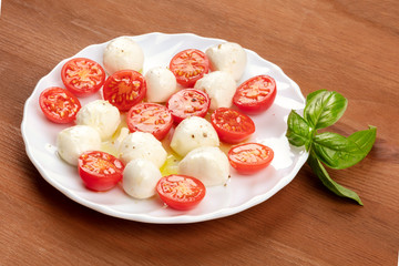 A photo of a plate of Italian Caprese salad with Mozzarella cheese, cherry tomatoes, and basil leaves