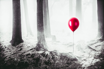 high contrast image of a red balloon in the woods