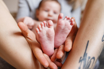 mother hold feets of newborn baby. Cute photo of baby boy. Childhood concept