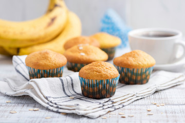 Healthy banana muffins with oat flakes on white table