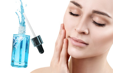 Beautiful face of young woman near blue cosmetic bottle.