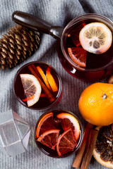 Mulled wine in glasses with orange and spices with gray scarf.