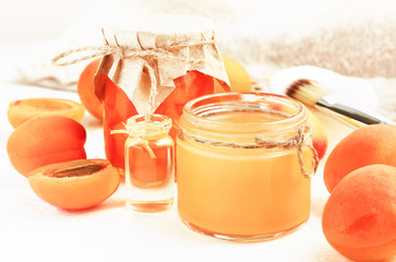 Nourishing skin care mask from fresh orange apricot fruit pulp jars, aromatic essential oil beauty treatment.