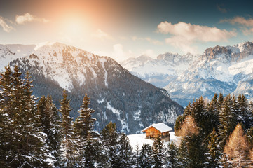 Wooden house in the winter mountains at sunset. Dolomite Alps, Val di Fassa, Italy