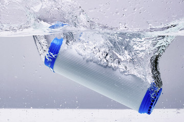 New carbon filter cartridge for house water filtration system isolated on white background. Splash....