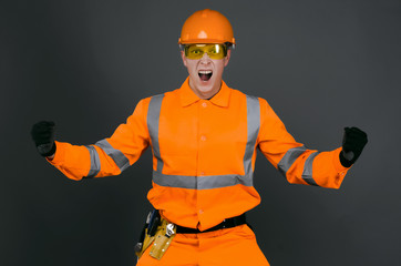 Fototapeta premium Angry builder foreman in the hardhat is shouting and screaming isolated on gray background. Construction problems.