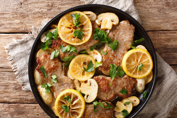 Italian main course veal scaloppini cooked with mushrooms and lemons in a spicy sauce, close-up. horizontal top view