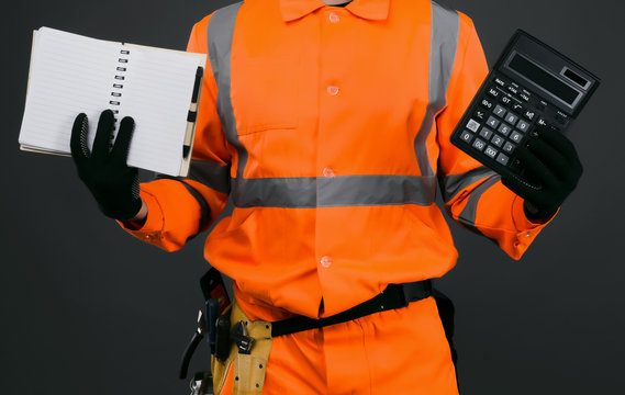 A construction worker with a calculator and a blank notebook in his hands. Cost calculation of repair or construction.