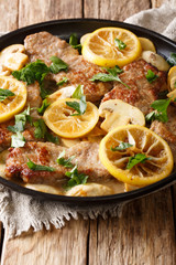 Italian veal scaloppini with mushrooms and lemons in a sauce close-up in a frying pan. vertical