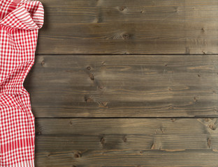 Fototapeta na wymiar Red checkered dishcloth on brown rustic wooden plank table flat lay top view from above
