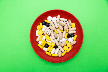 Top view of Bunch of pills in the red plate on green background