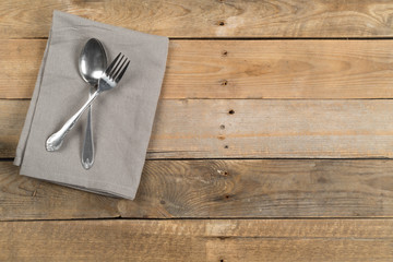 Grey dishcloth with fork and spoon silverware on brown rustic wooden plank table flat lay top view from above