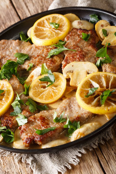 Lemon veal scaloppini with mushrooms in a sauce close-up in a pan. Vertical