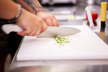 Obraz na płótnie Canvas Chef slicing greenery on white cutting table. Fresh vegetables