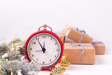 Vintage alarm clock, wrapped  presents, decorative golden pine cones and fir tree branches on white textured background.