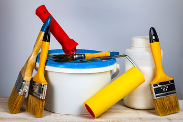 Paint can, roller and brush on the table.