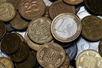 Ukrainian coins with one euro coin isolated on black background. Close-up view. Coins are located at center of frame. A conceptual image.