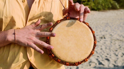 Fototapeta na wymiar Man playing on a drum with his hands, close up. Hands tapping a small drum