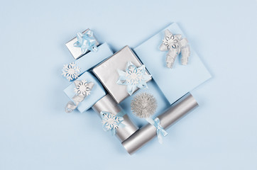 Modern soft minimalist heart shape - various blue and silver metallic gift boxes with shiny ribbons and bows on blue color backdrop, top view. Valentines day background.