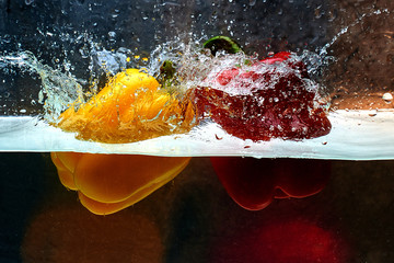 Two sweet bell peppers yellow and red in a splash of water. Cooking concept.