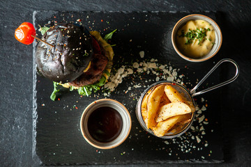 Fototapeta na wymiar Delicious black beef burger with soia sos and french fries. Classic gourmet snak