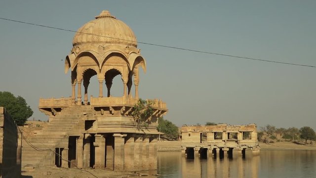 A long shot of an old royal cenotaph surrounded by water from a lake